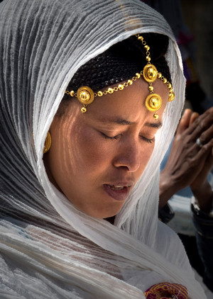Woman prays Woman with Gold Jewelry and a White Veil prays