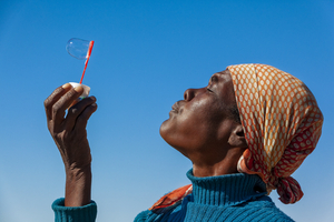 African woman making soap bubbles, Botswana