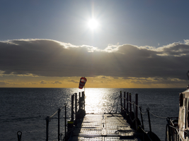 Bootssteg bei Sonnenaufgang über dem Meer an der Magellanstraße, Punta Arenas, Chile