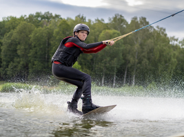 Junger Mann, athletisch, fährt rasant mit Wakeboard, Wassersport, Wasserski und Wakepark, Stráž pod Ralskem, Tschechien