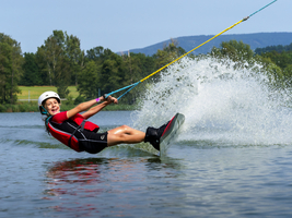Junge oder Mädchen, fröhlicher Sommerurlaub mit Wakeboard, Wasser spritzt, rote Schwimmweste, Wasserski und Wakepark, Stráž pod Ralskem, Tschechien