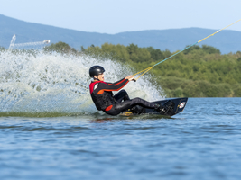 Junger Mann bei sportlicher Fahrt mit Wakeboard im See, Wassersport, Wasserski im Wakepark, Stráž pod Ralskem, Tschechien