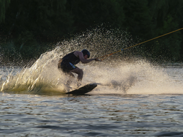 Mann mit Wakeboard im spritzenden Wasser, Abendlicht, Wassersport und Wasserski im Wakepark, Stráž pod Ralskem, Tschechien