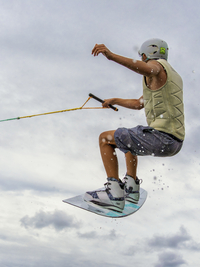 Junger Mann bei Sprung mit Wakeboard, Wassersport, Wasserski im Wakepark, Stráž pod Ralskem, Tschechien