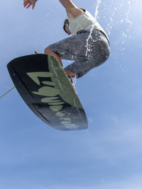 Junger Mann bei Sprung und Flug mit Wakeboard, Wassersport und Wasserski im Wakepark, Stráž pod Ralskem, Tschechien