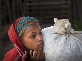 Girl in thought with grain sack, Ethiopia, Africa