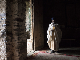 Priest with cross on door in dark light, Gondar, Amhara Region, Ethiopia, Africa