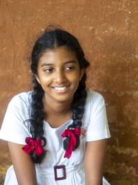 Singhalesisches Schulmädchen mit weißer Kleidung, schwarzen Zöpfen und roten Schleifen, Sri Lanka