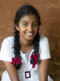 Singhalesisches Schulmädchen mit weißer Kleidung, schwarzen Zöpfen und roten Schleifen, Sri Lanka