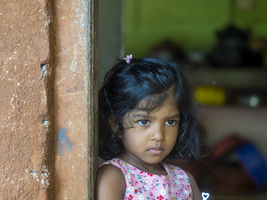 Kleines singhalesisches Mädchen mit großen Augen und schwarzen Haaren steht in Tür, Sri Lanka