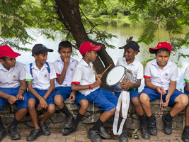 Schulkinder Schuluniform sitzen auf Mauer und trommeln, Sri Lanka