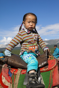 Mongolisches kleines Mädchen im Pferdesattel, Mongolei