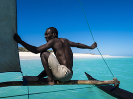 Man sitting on outrigger boat, turquoise sea, pirogue, Ambatomilo, Madagascar