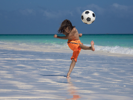 Boy plays soccer and shoots the ball on Ambatomilo beach, Madagascar