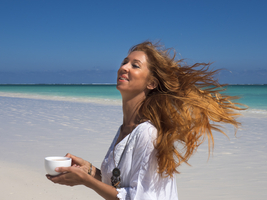 Woman with red hair blowing in the wind, drinking tea on the beach, Ambatomilo, Madagascar