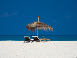Two loungers and an umbrella in the white sand on the beach, Ambatomilo, Madagascar