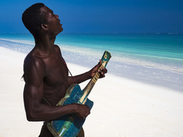Musician plays on old mandolin on the white beach of Ambatomilo, Madagascar