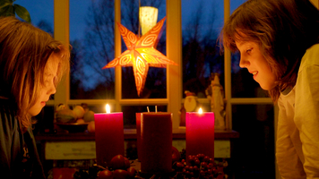 Children in Advent with candles on the table, look into the light, Germany