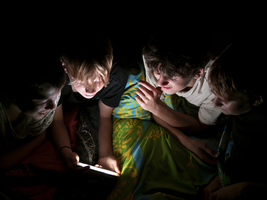 Jungs liegen nachts im Bett zusammen und schauen in ihr Handy, Deutschland