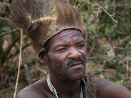 Bushman with headdress, sitting in the bush, looking lost in thought, portrait, Tanzania