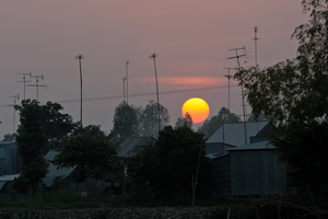 Sonnenuntergang hinter Dächern und alten Fernsehantennen, Mekong Delta, Vietnam