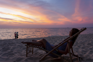 Frau liegt in Bambus-Liegestuhl in Abendstimmung am Strand, blickt übers Meer, Phu Quoc, Vietnam