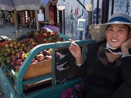 Lachende Verkäuferin, exotische Früchte auf Anhänger in den Straßen von Dali, Yunnan, China