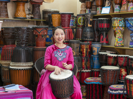 Junge chinesische Frau trommelt und singt, Mädchen im Trommel Geschäft, historische Altstadt von Lijiang, Yunnan, China