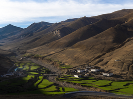 Dorf zwischen grünen Terrassen, Reisanbau und Landwirtschaft im Hochland von Tibet, China