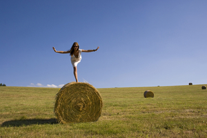 Woman in balance on straw bale, Saxony, Germany