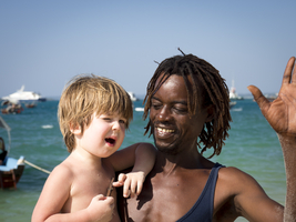 White little boy, colored man with locking curls, give me five, Zanzibar, Tanzania, Africa
