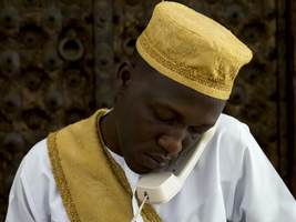 Arab man with yellow cap talking on the phone, white clothes, yellow scarf, reception, Zanzibar, 2017