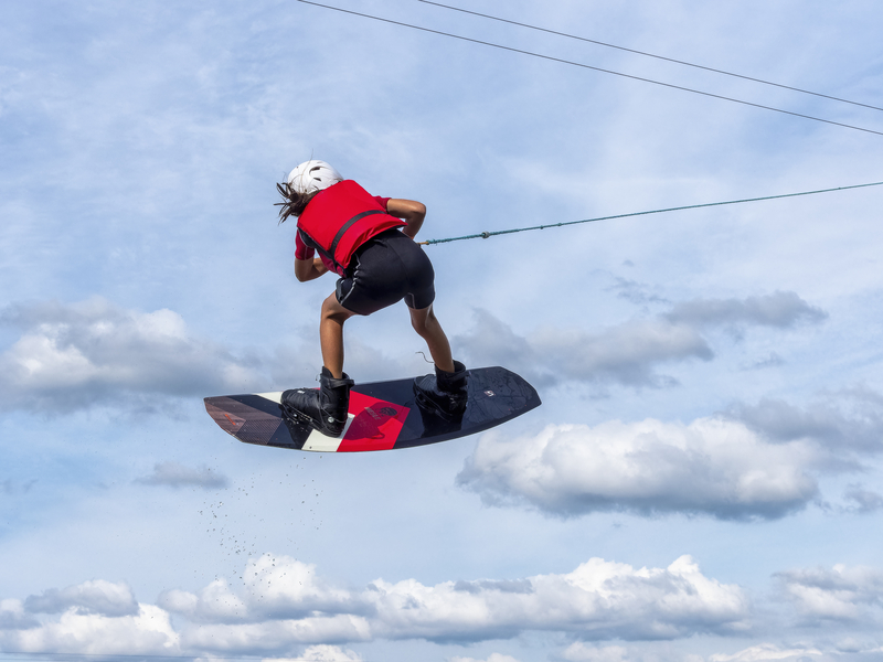 Mann mit Wakeboard im spritzenden Wasser, Abendlicht, Wassersport und Wasserski im Wakepark, Stráž pod Ralskem, Tschechien